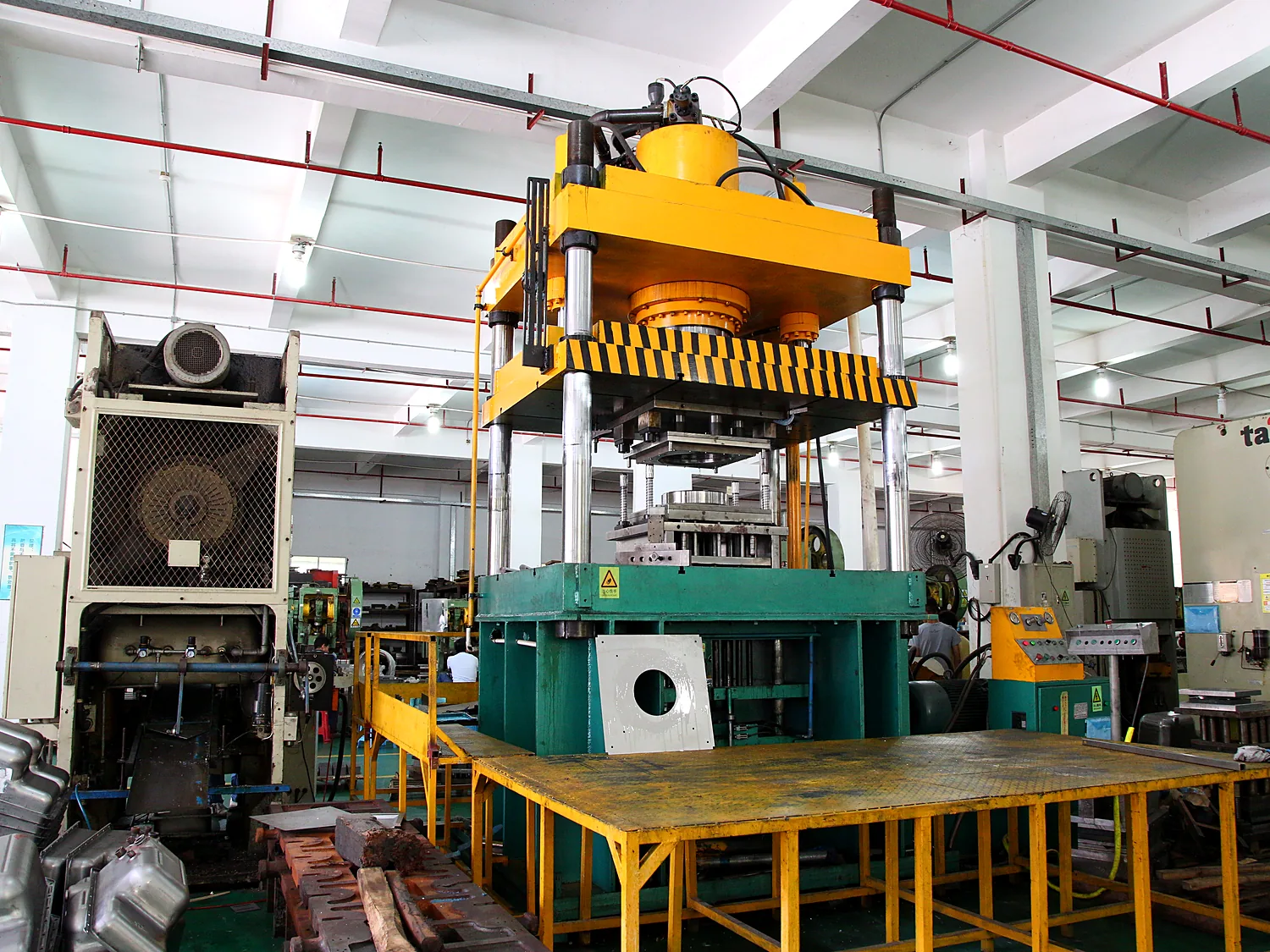 Large press under an overhead yellow crane