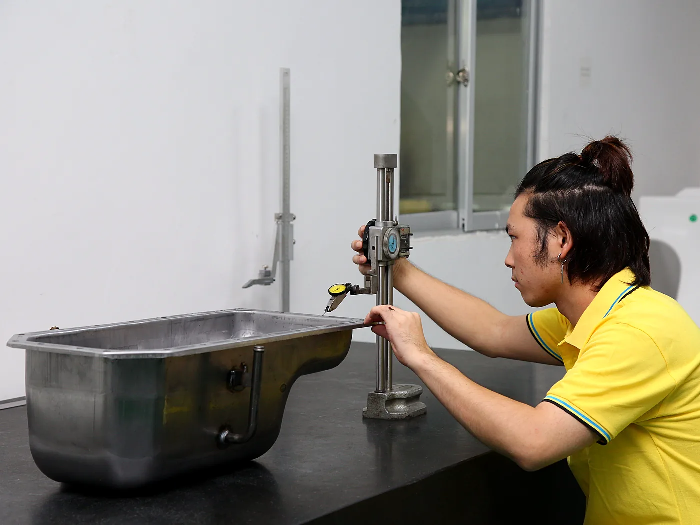 Technician measuring a metal housing with a height gauge